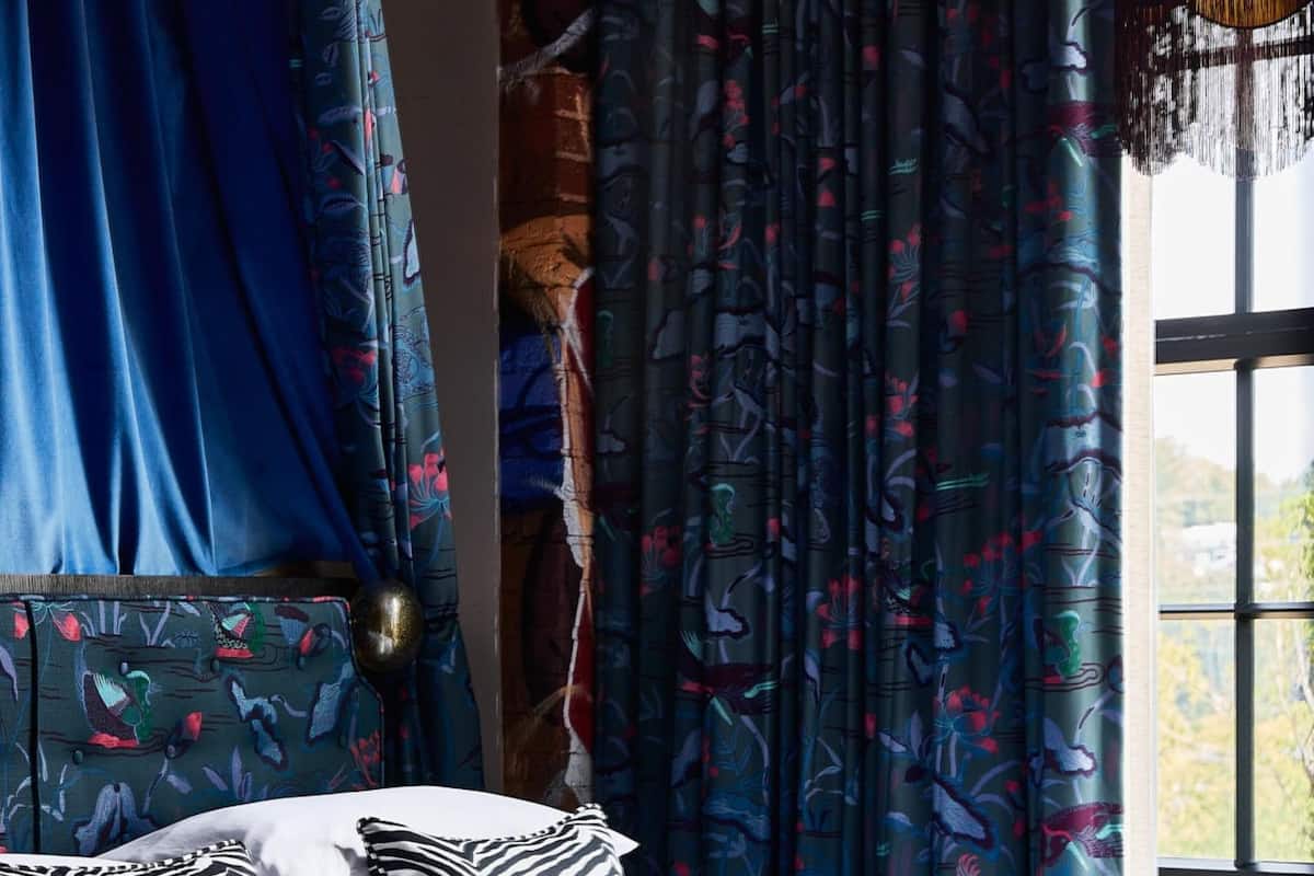 A bedroom with a bed, zebra-patterned pillows, and curtains with a bird pattern.