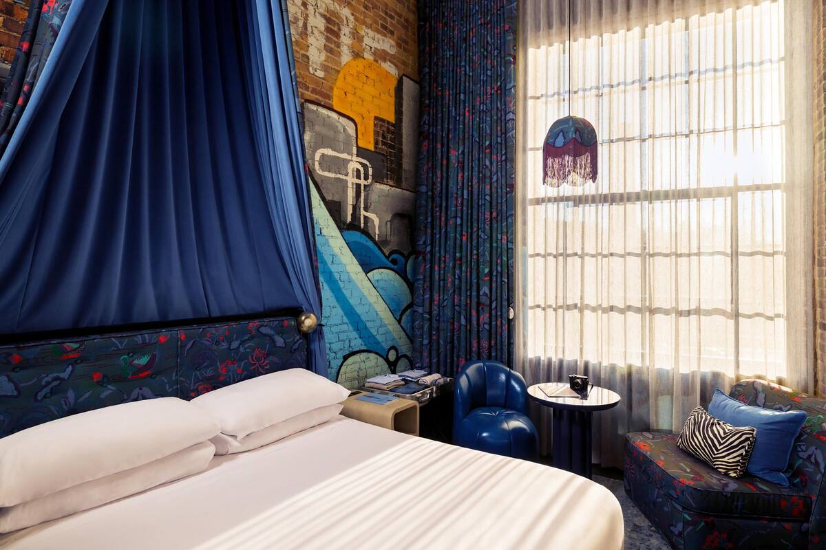 A hotel room with a bed, a small table, a chair, and a sofa.
