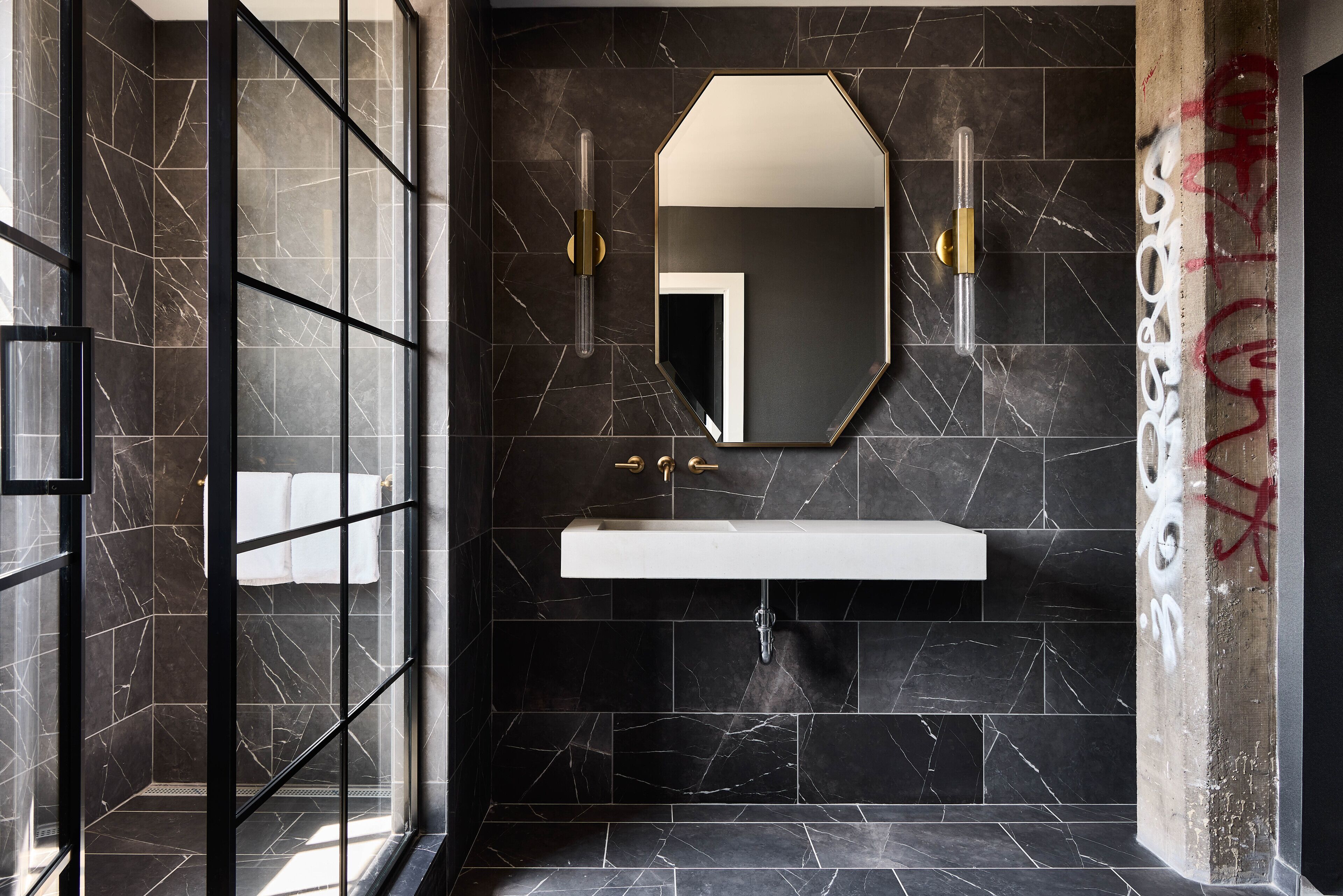 A modern bathroom with a glass shower enclosure, a white sink, and a large mirror.