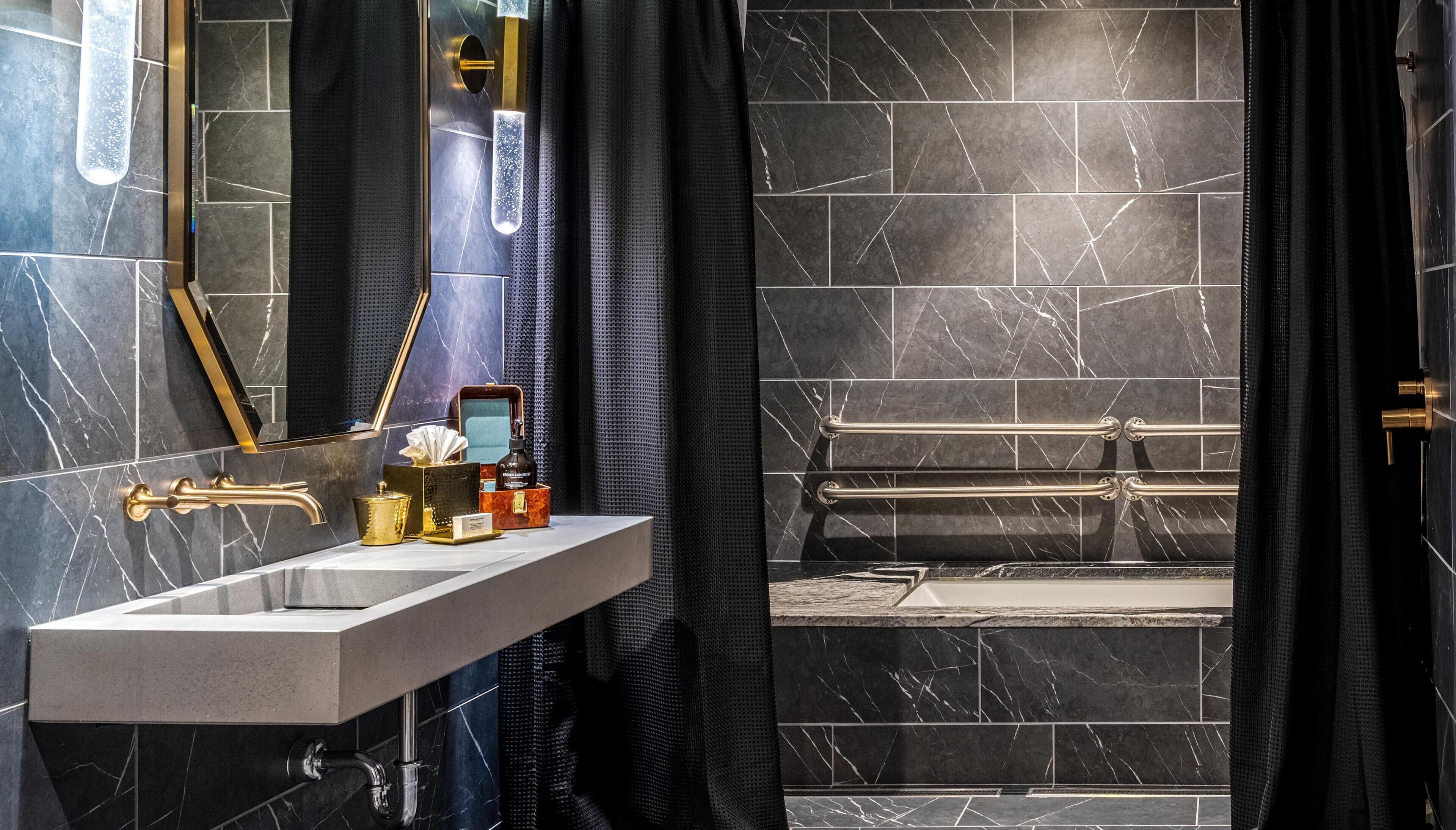 Une salle de bain moderne avec un lavabo en marbre, une douchette à main et une paroi de douche en verre.