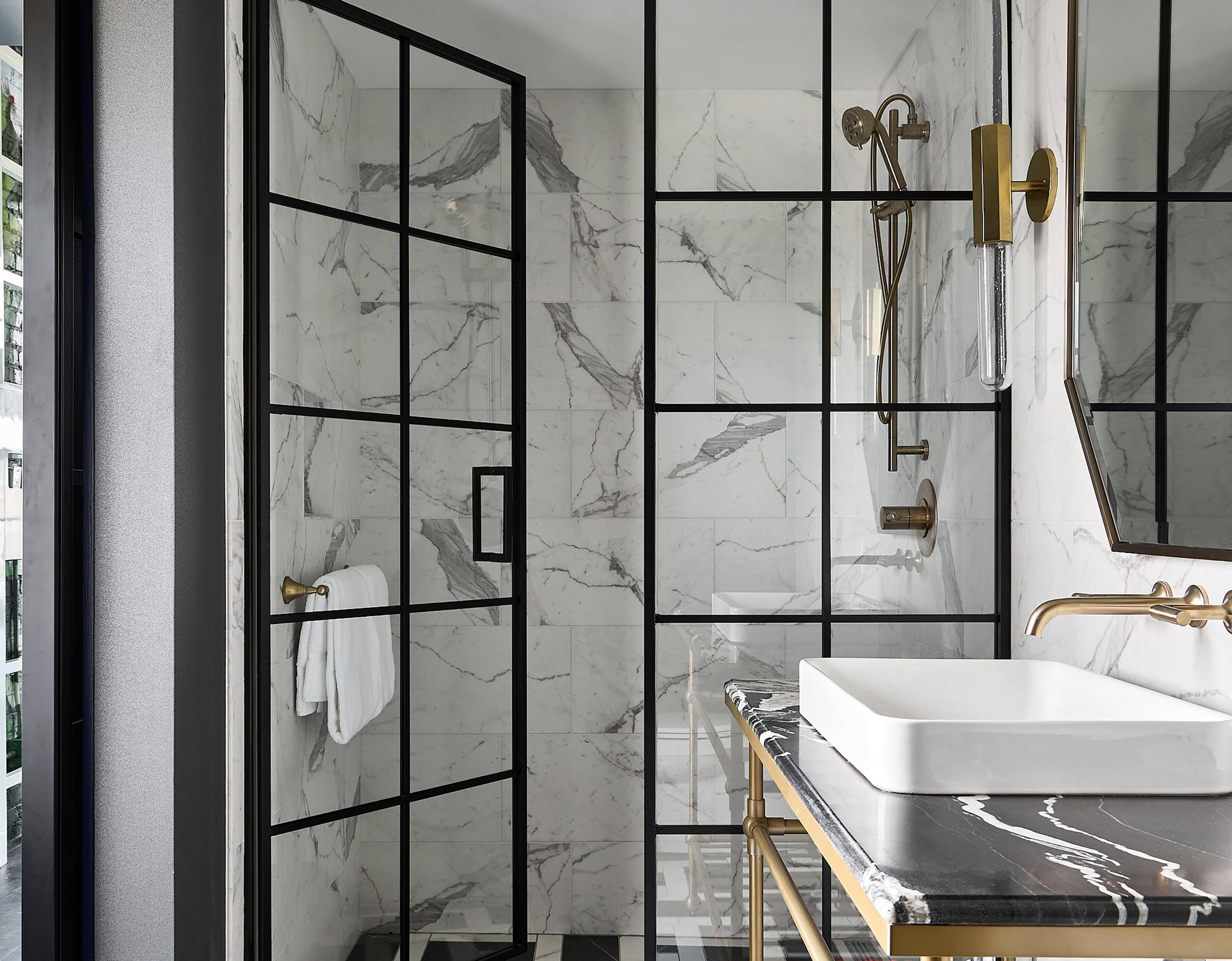 A modern bathroom with a large mirror, a white sink, and a shower area.