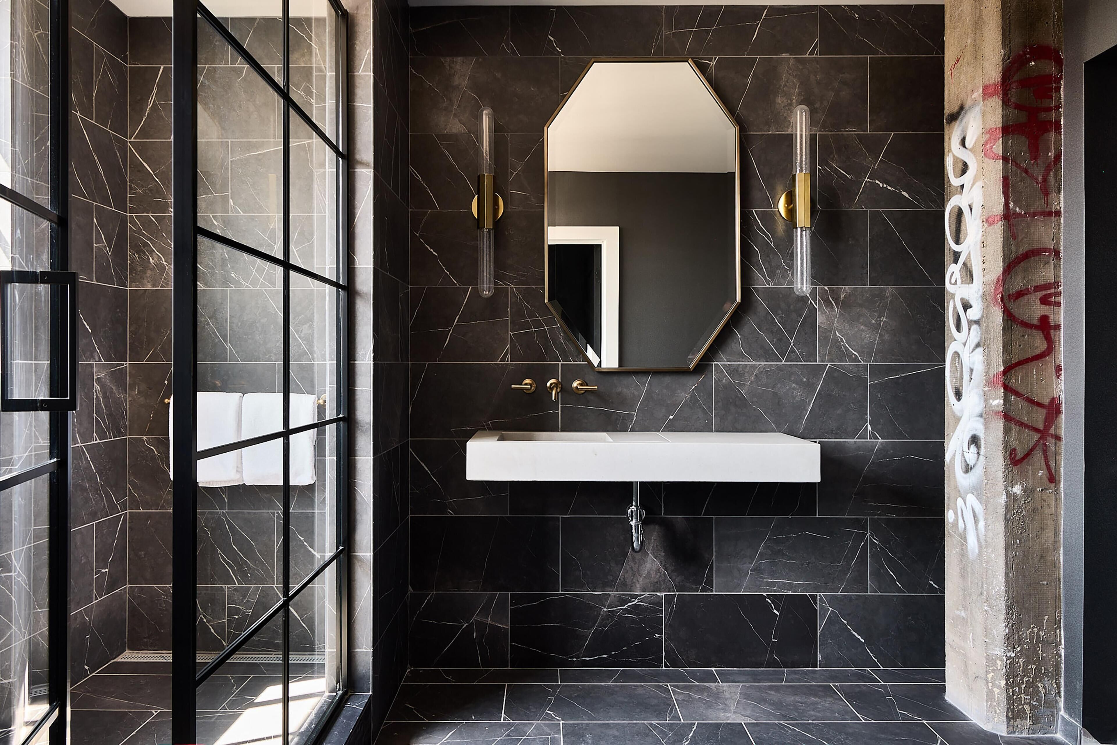 A modern bathroom with a glass shower enclosure, a white sink, and a large mirror.