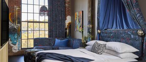 A bedroom with a large bed, a sofa, and a window with curtains.