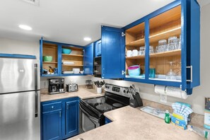 Uma cozinha moderna com armários azuis, eletrodomésticos de aço inoxidável e prateleiras abertas.