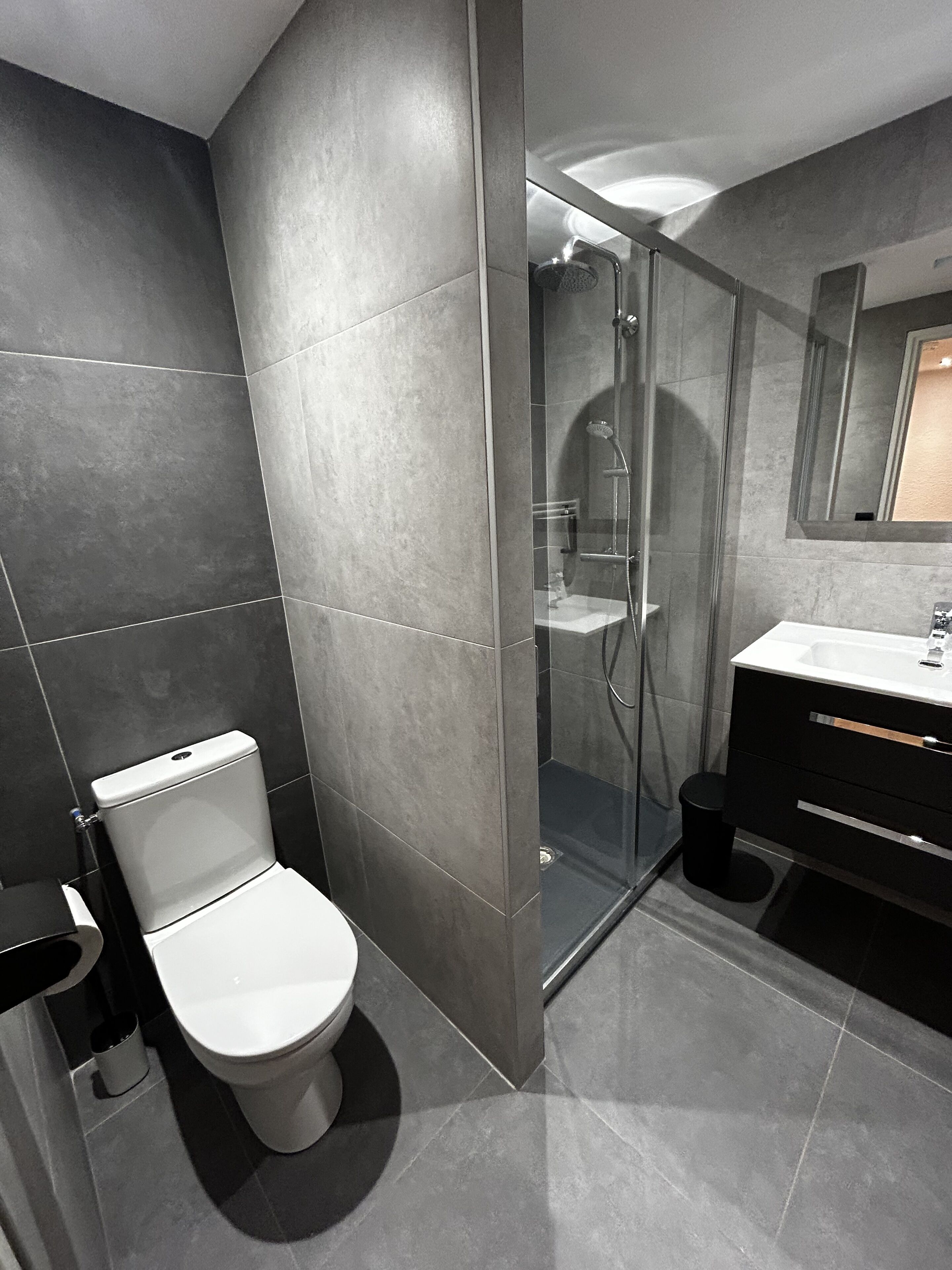 Une salle de bain moderne équipée de toilettes, d’une douche et d’un lavabo.