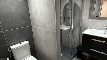 Une salle de bain moderne équipée de toilettes, d’une douche et d’un lavabo.