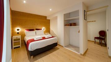 A bedroom with a wooden headboard, a bed with white linens, a nightstand, a wardrobe, and a chair.
