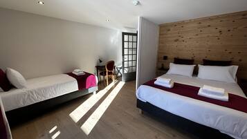 Une chambre d’hôtel avec deux lits, un bureau, une chaise et une tête de lit en bois.