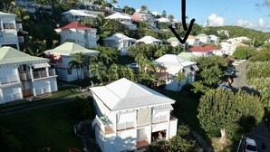 A residential area with houses featuring red roofs and white exteriors, surrounded by greenery and palm trees. - Guadeloupe, Saint-François Anse des Rochers, 1/4 villa , vue mer citerne wifi pr (Saint-François)