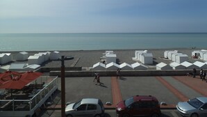 A beachside parking area with several white beach huts and a row of cars.