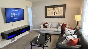 A living room with a flat-screen TV, a sofa, a coffee table, and a lamp. - EKO Stay - Your Home Away From Home (Wauwatosa)