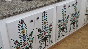 A kitchen with a granite countertop, a yellow electric kettle, and a white cabinet with floral designs. - Medina town house (Sousse)