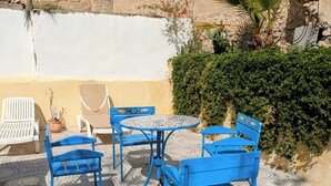 A patio with blue metal chairs and a round table, surrounded by patterned tiles. - Medina town house (Sousse)