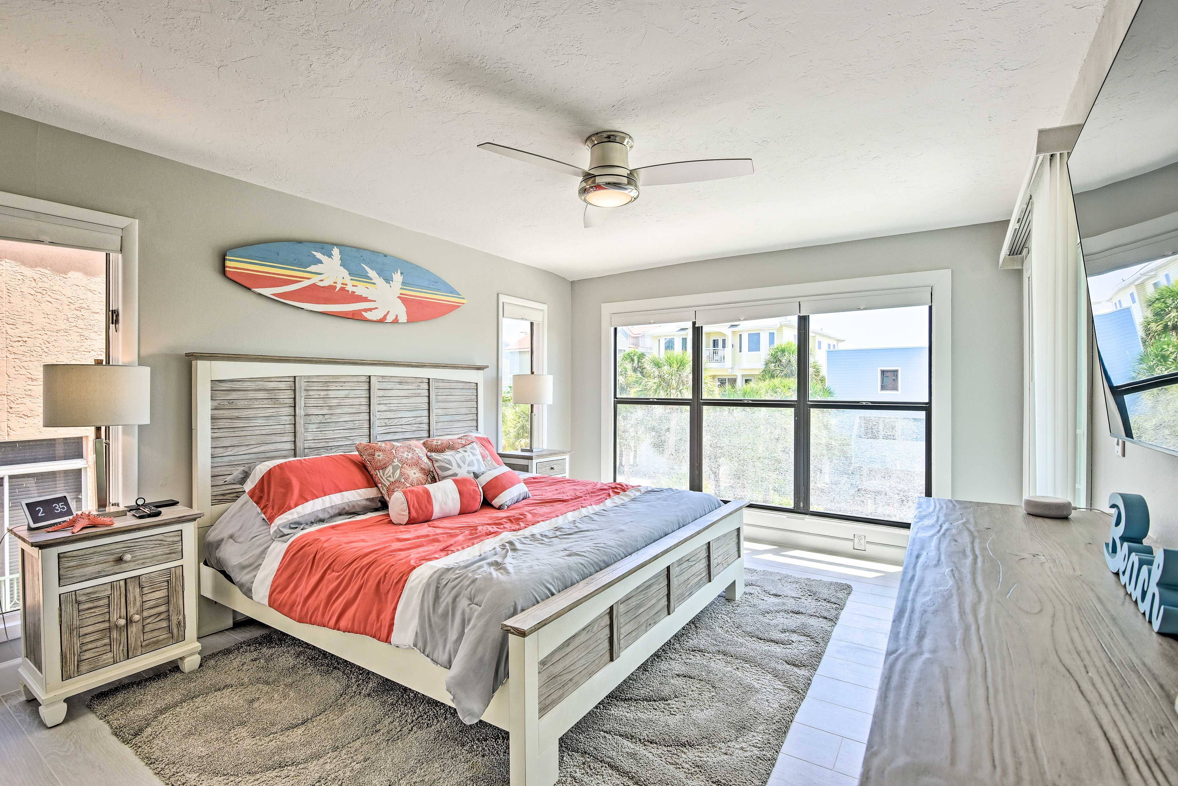 A bedroom with a bed, nightstands, a ceiling fan, and a large window.