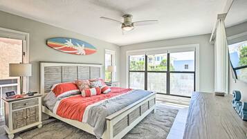 A bedroom with a bed, nightstands, a ceiling fan, and a large window.