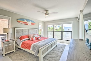 A bedroom with a bed, nightstands, a ceiling fan, and a large window. - Coastal Surfside Swank by Beachside Management (Siesta Key)