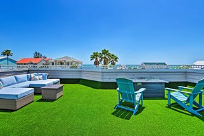 An outdoor patio with a sectional sofa, two blue Adirondack chairs, and a small table. - Coastal Surfside Swank by Beachside Management (Siesta Key)