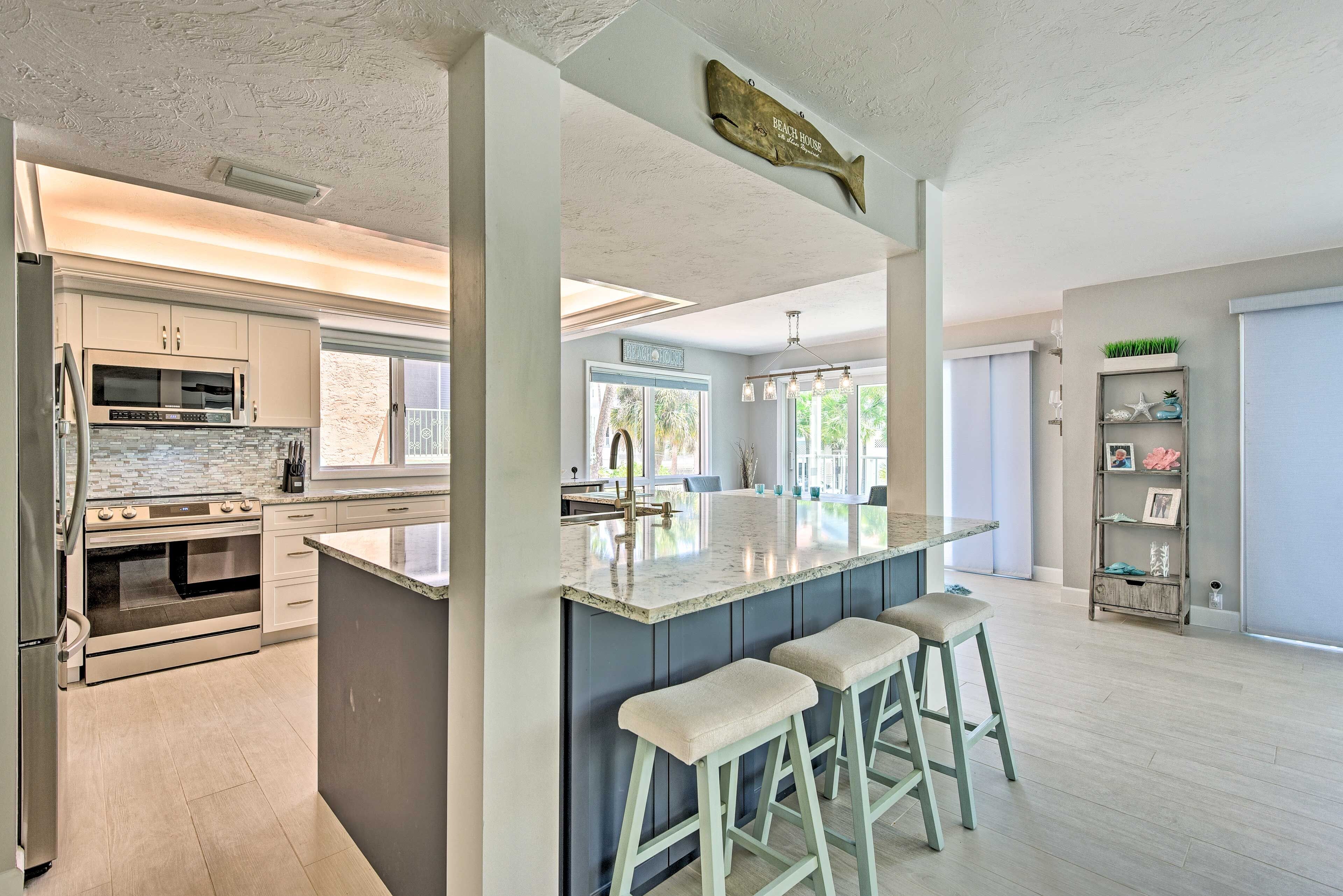 A modern kitchen with a large island, stainless steel appliances, and a view to the dining area.