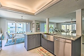 A modern kitchen with grey cabinets, stainless steel appliances, and a large window. - Coastal Surfside Swank by Beachside Management (Siesta Key)