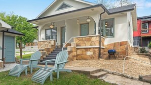 A two-story house with a stone exterior, a front porch with steps, and two Adirondack chairs. - Herons Lake View Hideaway (Rockaway Beach)