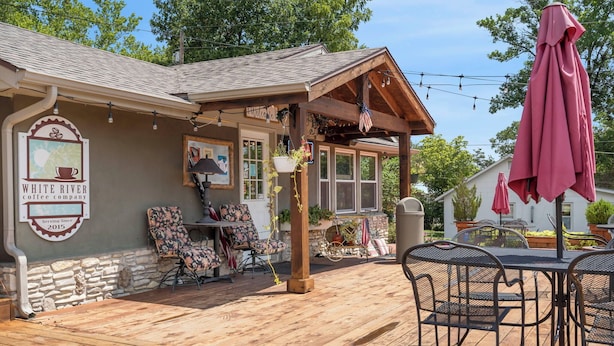 A cozy outdoor seating area with a wooden deck, a covered patio, and a coffee shop sign. - Herons Lake View Hideaway (Rockaway Beach)