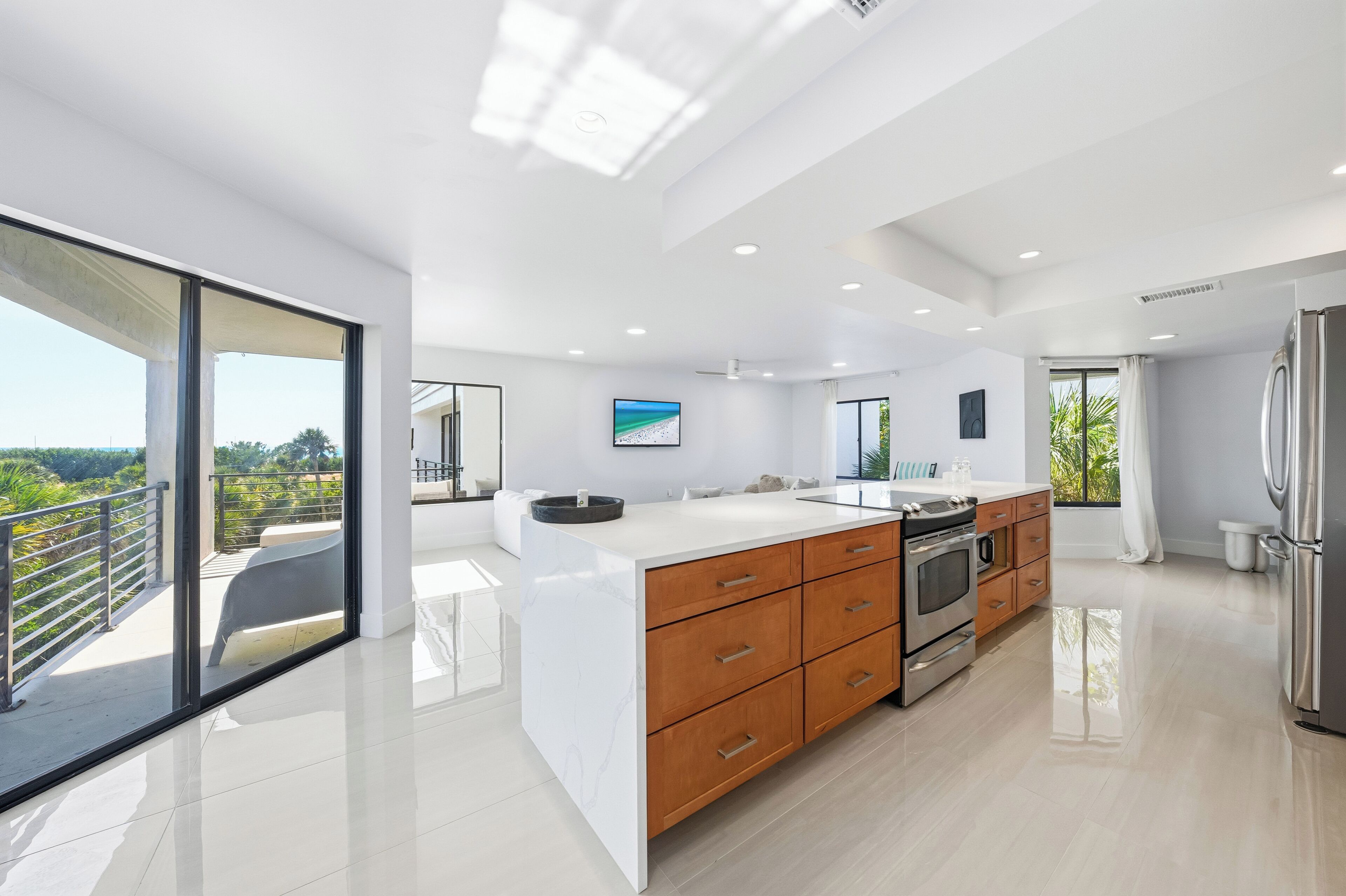 A modern kitchen with a large island, wooden cabinets, and stainless steel appliances.