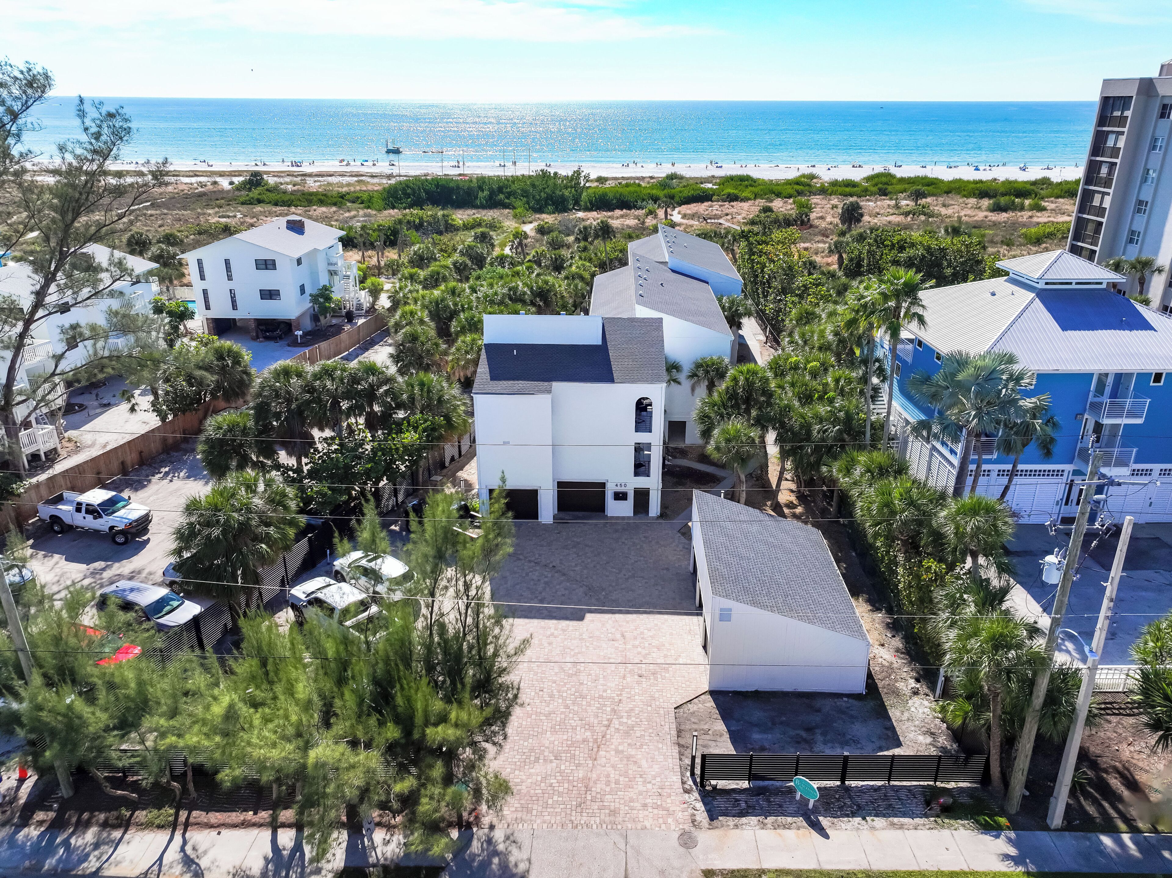 An aerial view of a coastal area with buildings, a beach, and a parking lot.