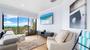A modern living room with a sofa, armchair, and a view of the outdoors through large sliding doors. - Just Beachy by Beachside Management (Siesta Key)