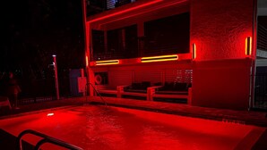 A swimming pool with a red-lit deck and a bench area. - Just Beachy by Beachside Management (Siesta Key)