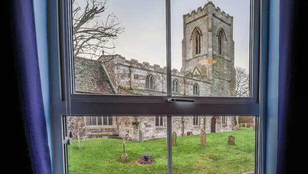 A view of a historic stone building with a tower through a window. - Coastguard Cottages (Hull)