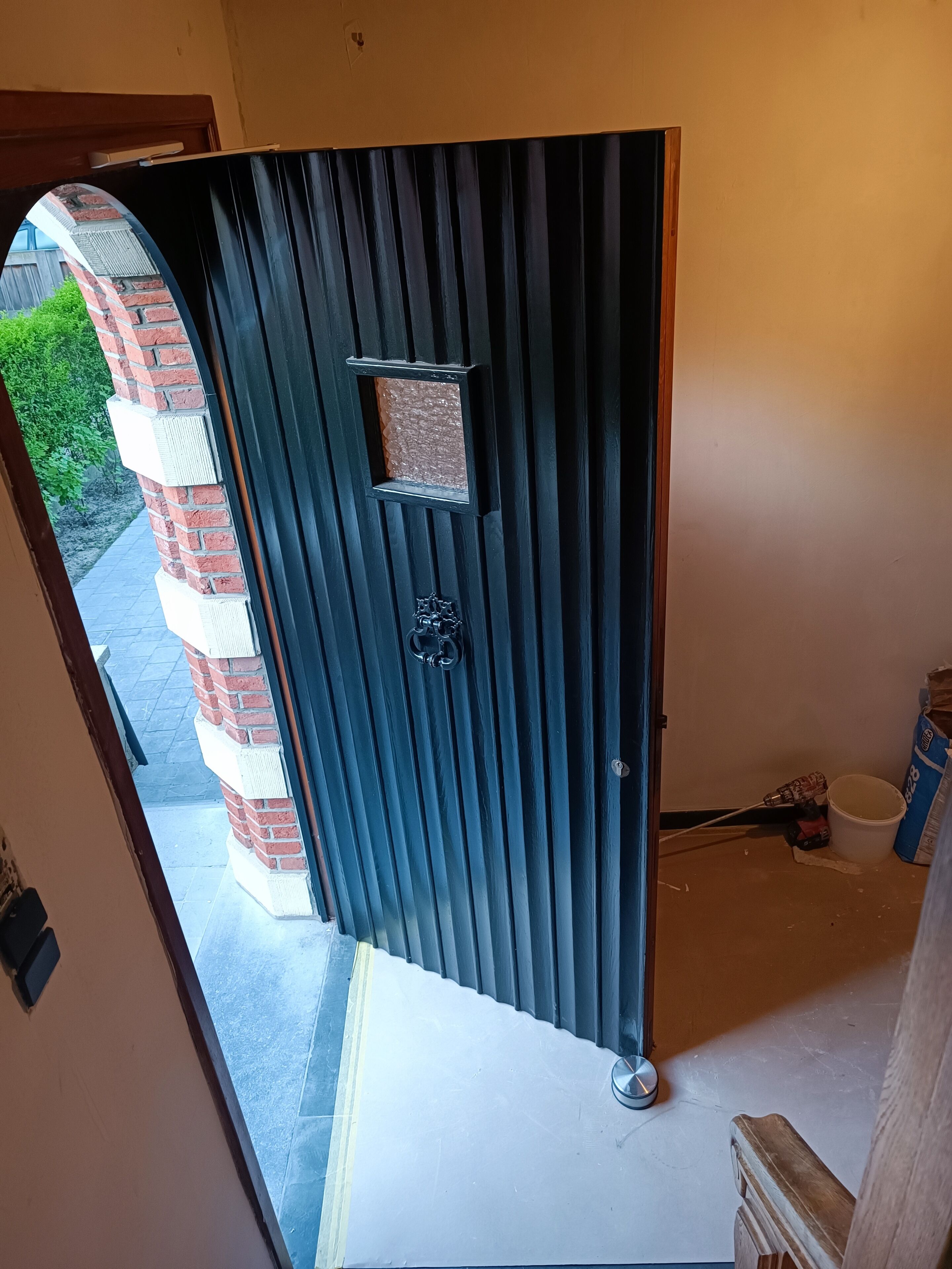 Une porte coulissante moderne, de couleur sombre, dotée d’une petite fenêtre et d’une serrure à clé.