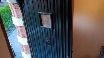 Une porte coulissante moderne, de couleur sombre, dotée d’une petite fenêtre et d’une serrure à clé.