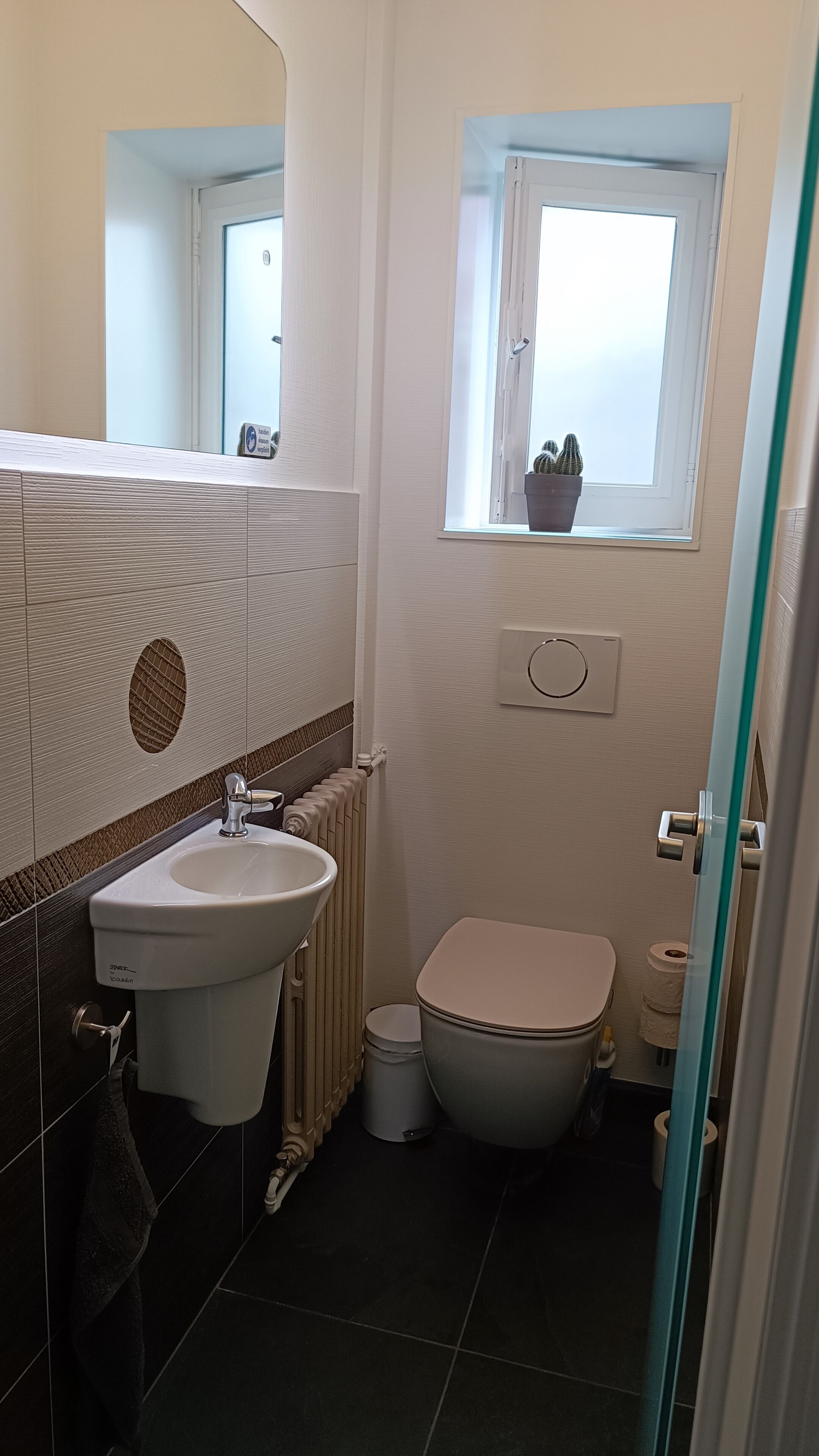 A bathroom with a white sink, toilet, and a window above the toilet.