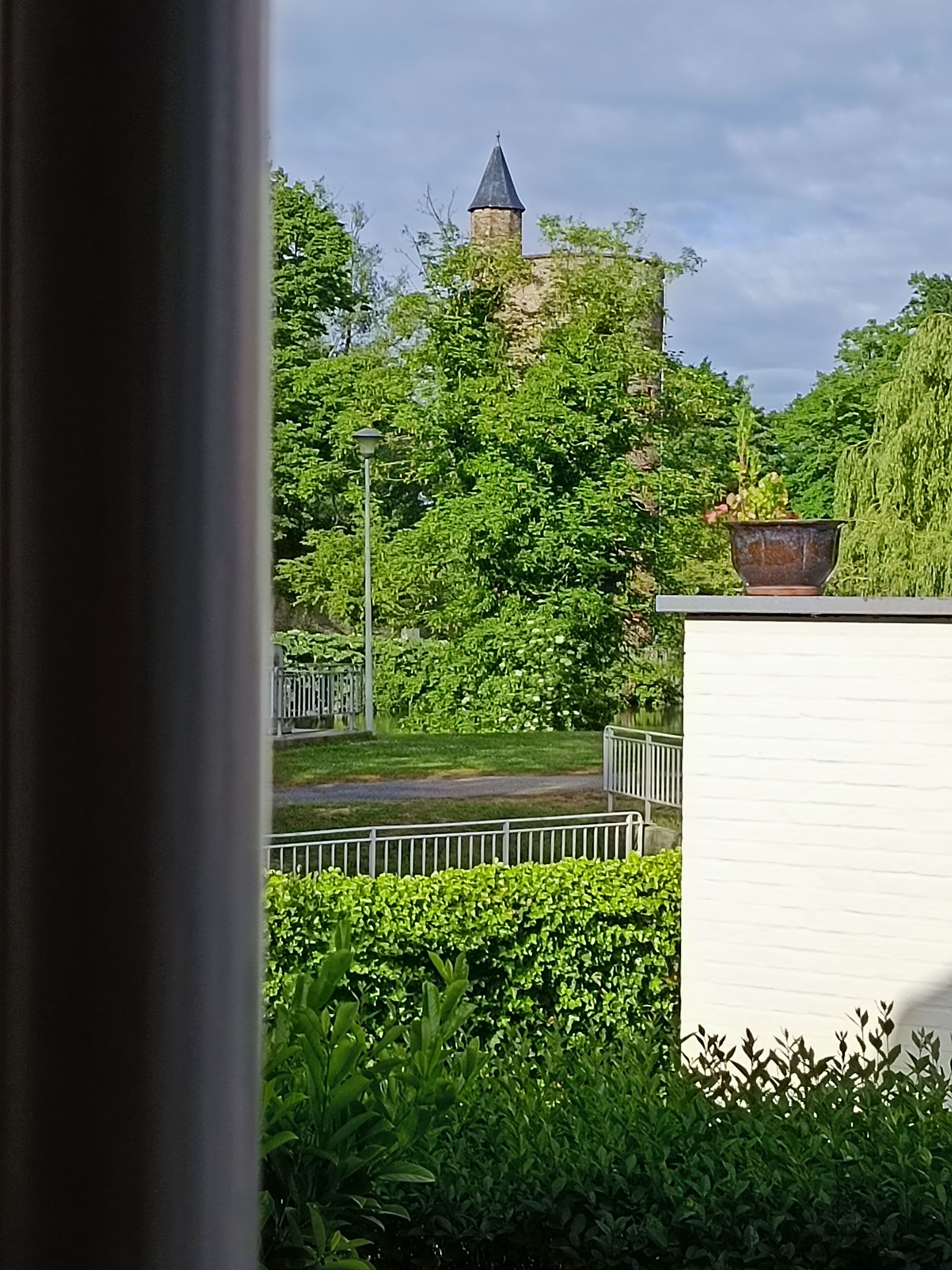 A view of a garden with a stone tower and lush greenery.