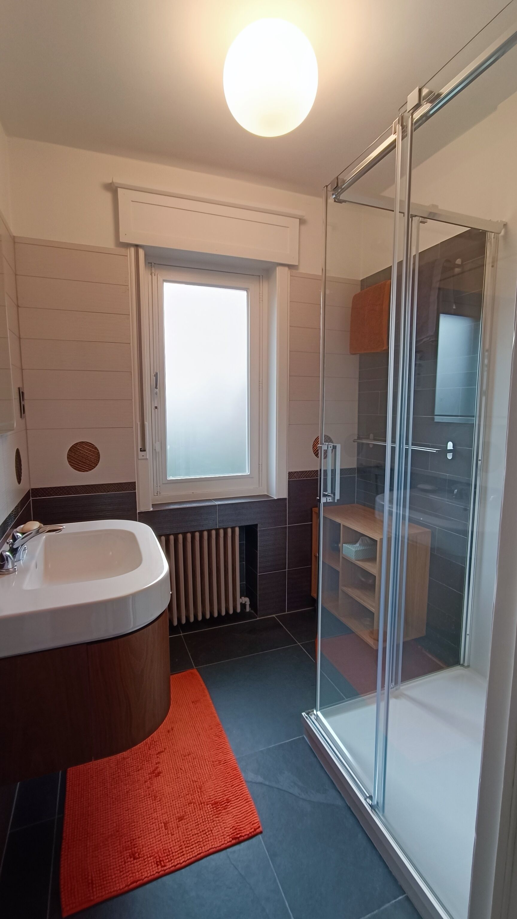 Ein modernes Badezimmer mit Duschkabine aus Glas, einer eingebauten Badewanne und einem Fenster mit Milchglas.