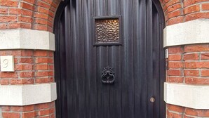 A black wooden door with a metal knocker, flanked by red brick walls and white trim. - Pearl in the heart of Bruges (Brugge)