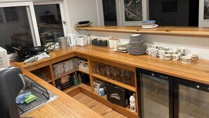 A kitchen with a wooden countertop, a refrigerator, and a sink.