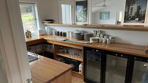 A kitchen with wooden countertops, a refrigerator, and a window overlooking a garden.