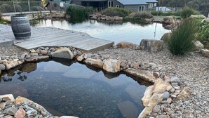 A pond with a wooden deck and a stone border.