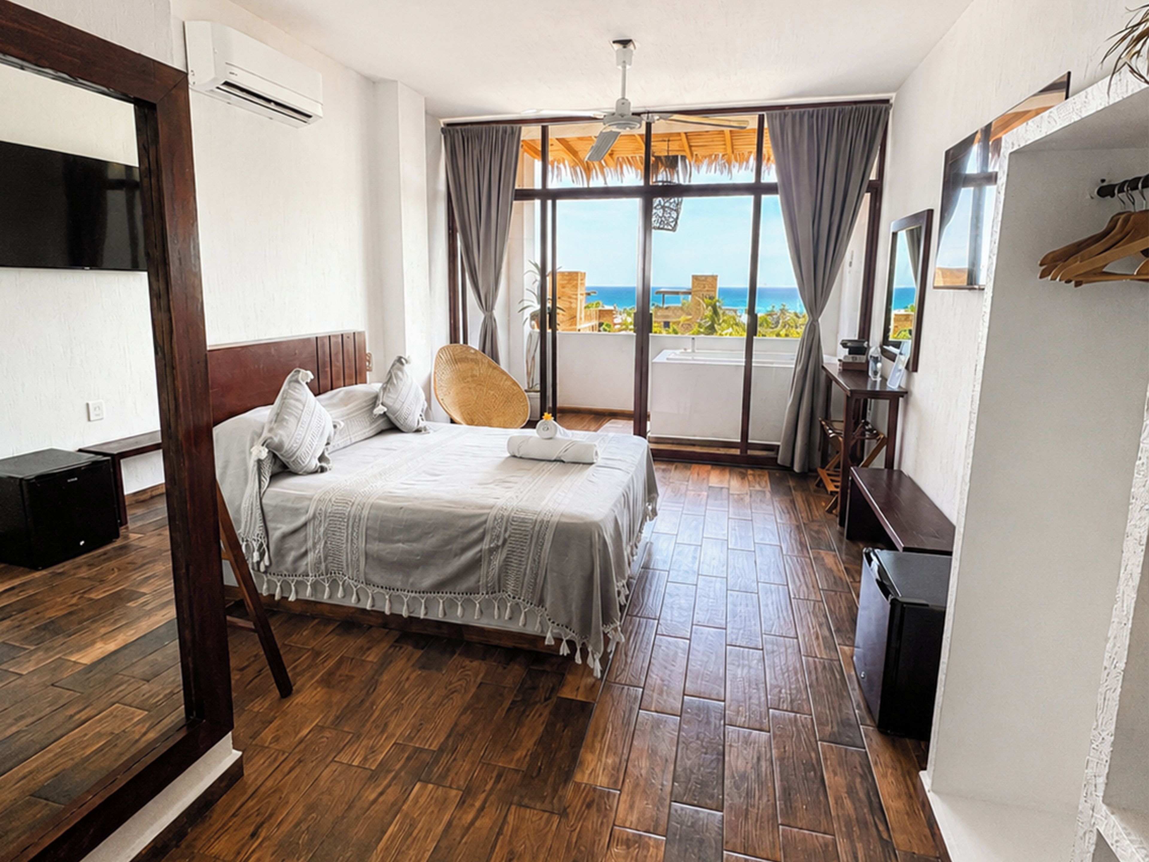 Ein Hotelzimmer mit Bett, Fernseher, Schreibtisch und Meerblick.