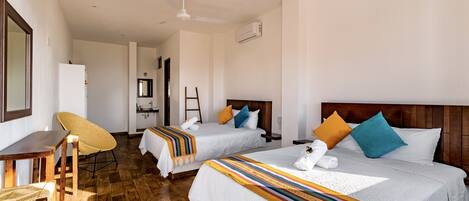 A hotel room with two beds, a wooden desk, a chair, and a ceiling fan.