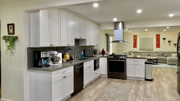 Una cocina moderna con armarios blancos, una isla central y una zona de comedor con sofá y mesa.