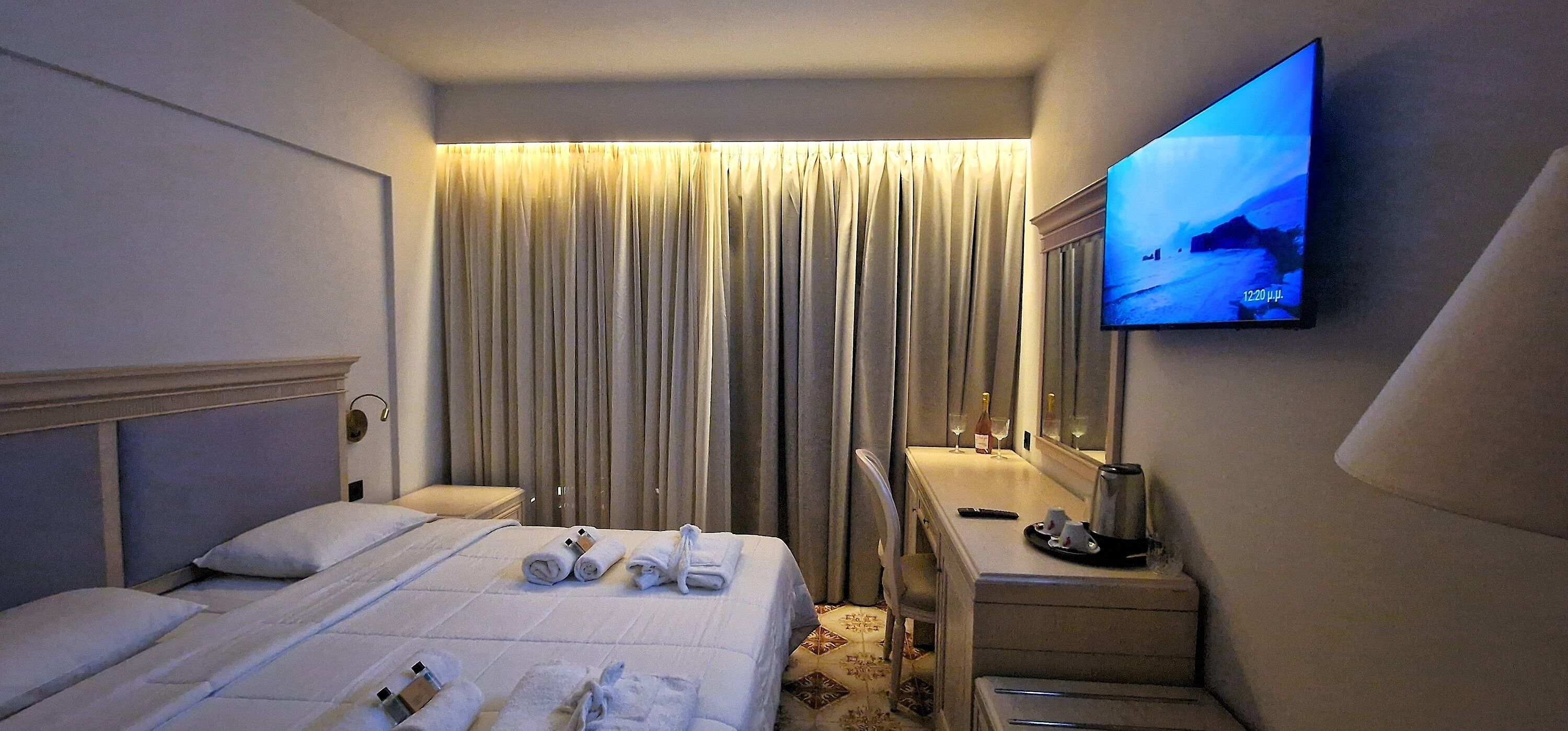 Ein Hotelzimmer mit Bett, Schreibtisch, Fernseher und Spiegel.