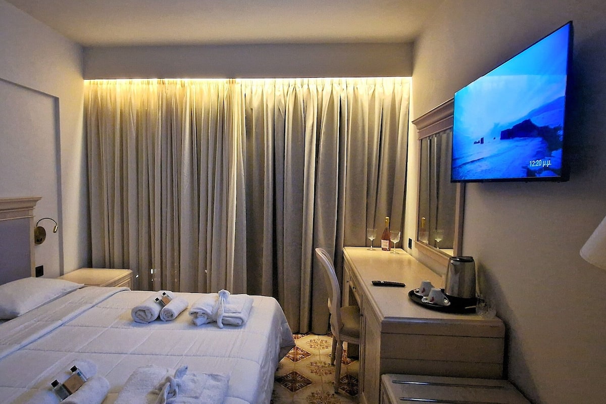 Ett hotellrum med en säng, ett skrivbord, en tv och en spegel.