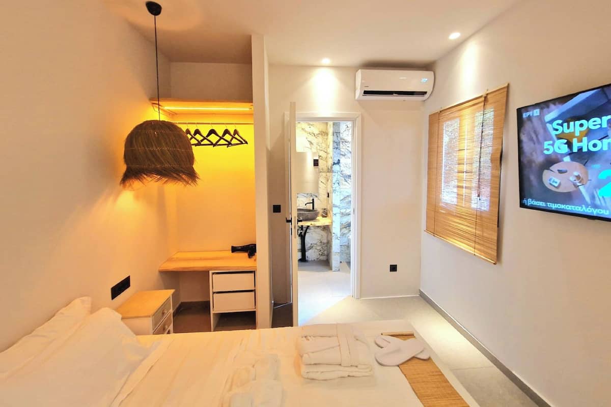 Una habitación de hotel con cama, escritorio, lámpara colgante, unidad de aire acondicionado y un televisor mostrando 'Super 5G Home'.