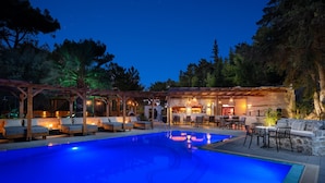 Un espace piscine aménagé pour la nuit, avec des chaises longues et un bar.