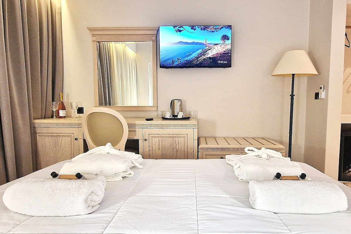 Una habitación de hotel con cama, escritorio, silla, televisor y chimenea.