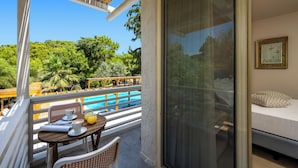 Un balcon avec une table, des chaises et une vue sur une piscine et un espace verdoyant.