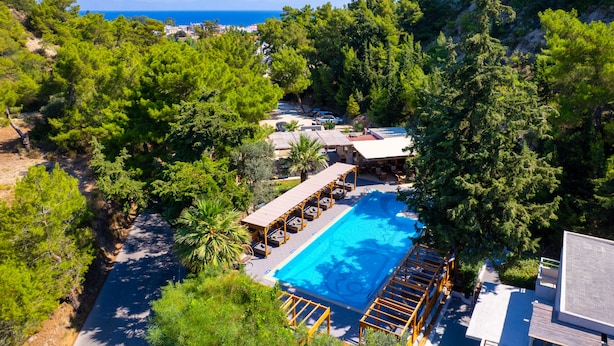Un complexe hôtelier doté d’une piscine, de chaises longues et offrant une vue sur la mer.