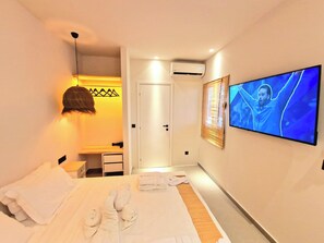 Ein Hotelzimmer mit Bett, Fernseher, Kleiderschrank und Tür.
